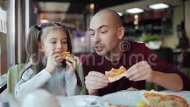 爸爸带着一个小女儿在披萨店里品尝香喷喷的披萨